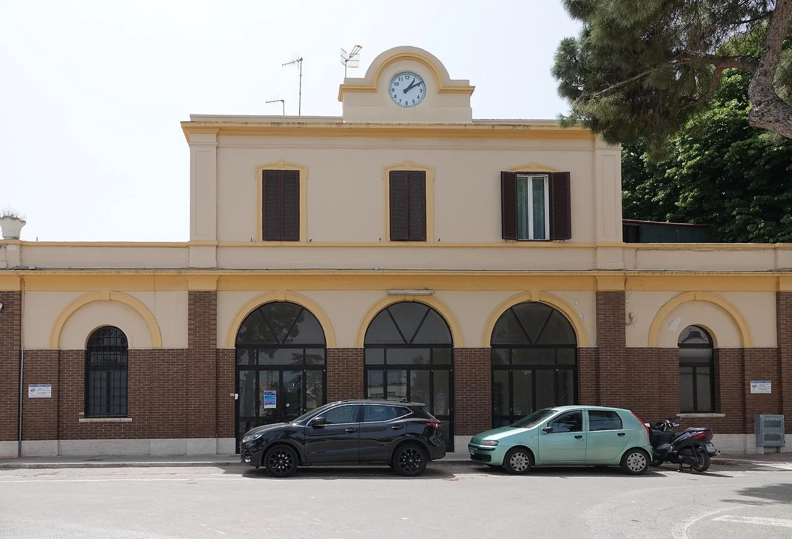 La facciata del fabbricato viaggiatori della stazione ferroviaria di Polignano a Mare, con l'orologio in cima e le arcate al piano terra