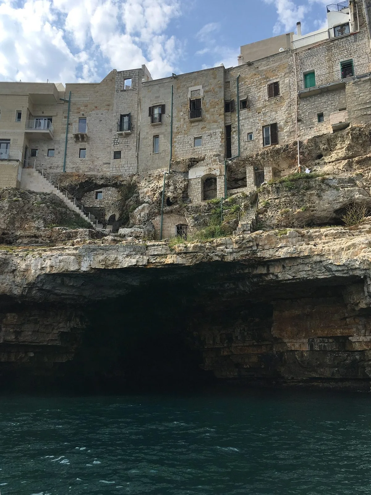 L'ingresso di una grotta marina alla base della falesia di Polignano a Mare, visto dal mare, con le case del borgo antico in cima
