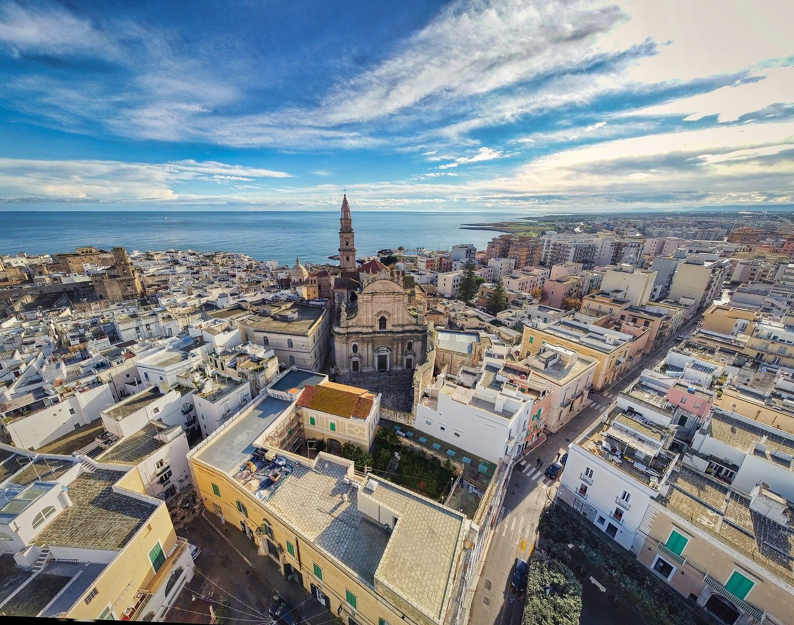 Veduta aerea del centro storico di Monopoli con la facciata barocca e il campanile della Basilica Cattedrale di Maria Santissima della Madia e il mare Adriatico sullo sfondo